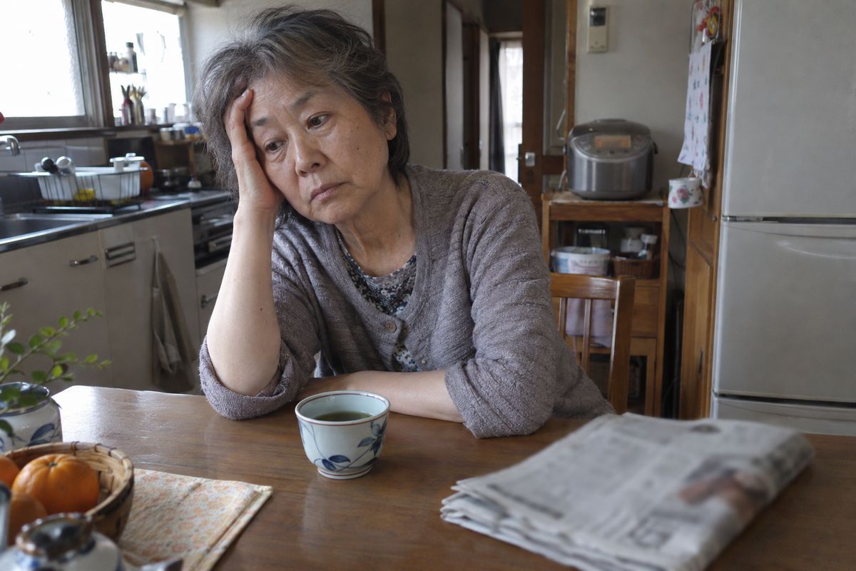 朝、お茶を前に頭がぼんやりして額を押さえる女性
